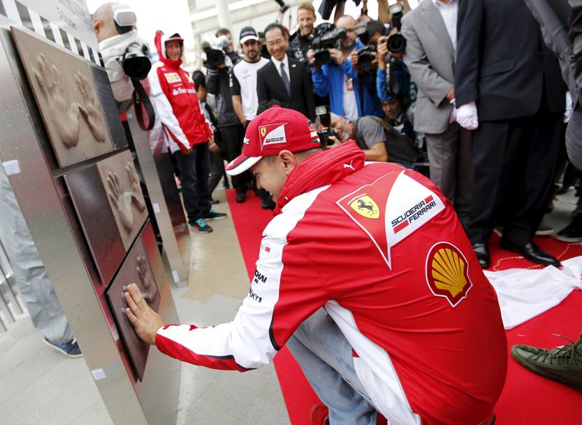 Il tedesco Sebastian Vettel, pilota Ferrari, imprime il palmo delle sue mani su un monumento proposto in occasione del GP del Giappone. Suzuka. (Reuters)